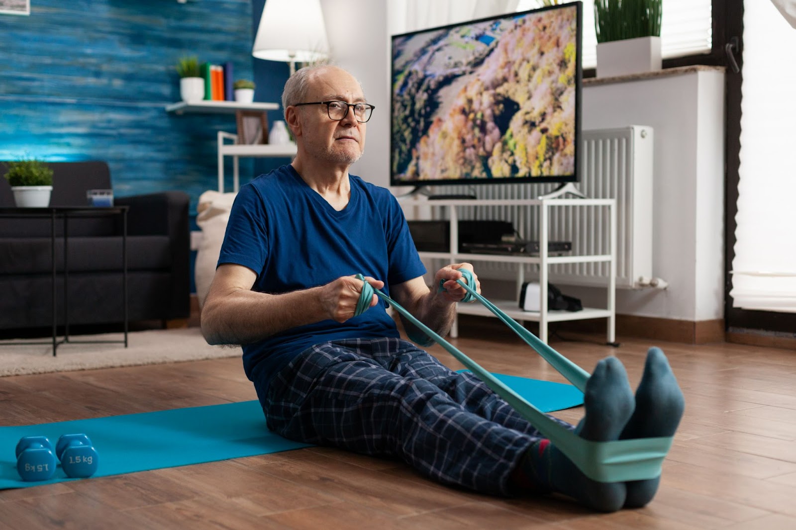 Older man doing resistance band exercises at home, promoting strength and balance for falls prevention in aged care